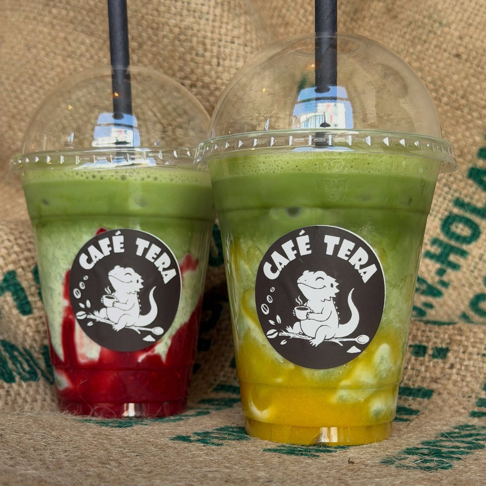 Zwei Matcha-Getränke mit Fruchtpüree in Bechern mit dem Café-Tera-Logo